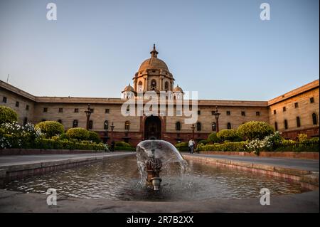 Ein malerischer Innenhof mit einem majestätischen Springbrunnen im Zentrum, umgeben von einem klassischen Gebäude mit aufwendiger Architektur und Säulen Stockfoto