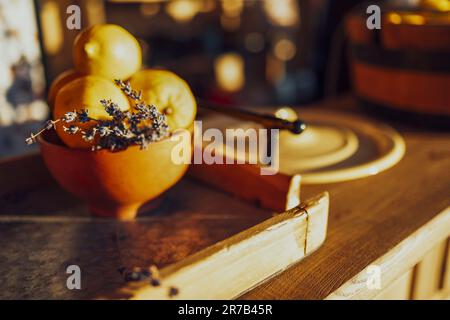 Extrime Nahaufnahme eines hölzernen Eimers voller frischer Zitronen und Lavendelzweig. Gelbe Zitrusfrüchte in einem großen Holzbecken, das auf dem steht Stockfoto