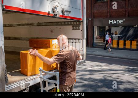 Ein Fahrer eines UPS-Kleinbusses entlädt am 14. Juni 2023 in London, England, einen Stapel Kisten aus dem Heck seines Fahrzeugs für ein nahegelegenes Unternehmen auf der Charing Cross Road in Westminster. Stockfoto