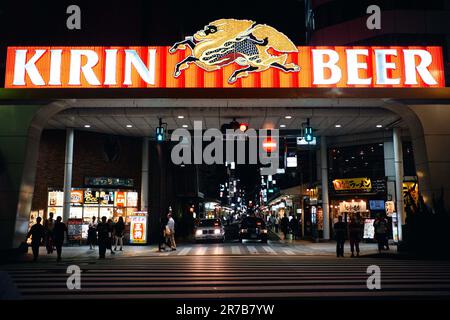 In Hiroshima, Japan, herrscht bei Nacht eine pulsierende Straßenszene mit Verkaufsautomaten und beleuchteten Schildern Stockfoto