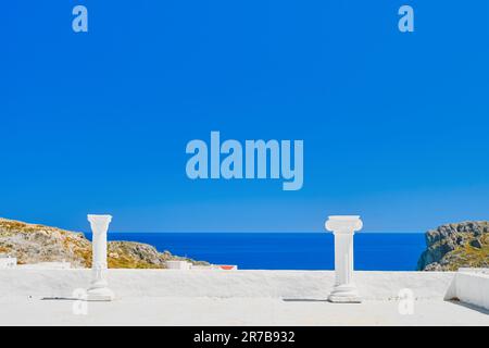 Zwei antike Säulen auf dem Dach des Hauses. Blick vom Dach des Hauses auf die Stadt Lindos, das smaragdgrüne Meer, die Insel Rhodos. Urlaub A Stockfoto