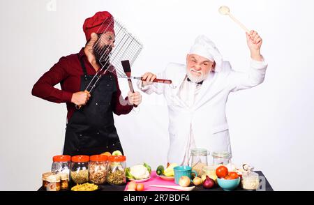 Professionelles kulinarisches Angebot. Köche in Uniform konkurrieren in der kulinarischen Show. Die Küche ist super. Kochwettbewerb. Kulinarische Schlacht. Zwei Köchinnen oder Bäcker, die sich streiten Stockfoto