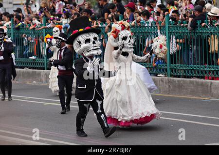 Darsteller mit riesigen Schädelmasken winken den Zuschauern während der Großen Parade der Toten zu, um den Urlaub von Dia de los Muertos auf dem Paseo de la Reforma am 29. Oktober 2022 in Mexiko-Stadt, Mexiko, zu feiern. Stockfoto