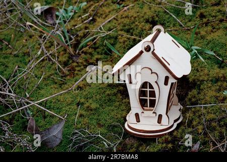 Kleines Holzhaus auf dem Rasen mit Moos steht am Nachmittag Stockfoto