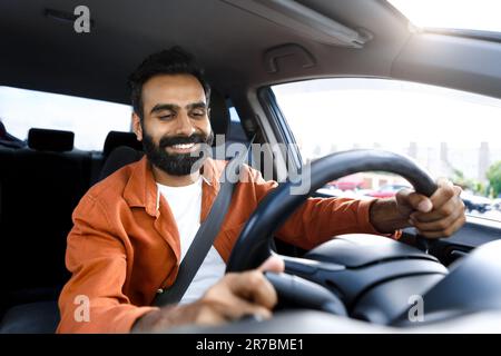 Selbstbewusster indianer, der sein neues Auto fährt, sitzt im Auto Stockfoto