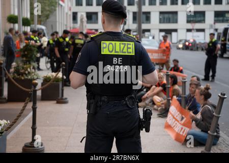 Berlin, Deutschland. 14. Juni 2023. Polizeibeamte stehen zwischen Aktivisten am Haupteingang des 'Ritz Carlton' Hotels am Potsdamer Platz. Mitglieder der Klimagruppe Last Generation saßen vor dem Haupteingang des Ritz-Carlton Hotels und einige friedlich aufgestellte Banner. Kredit: Paul Zinken/dpa/Alamy Live News Stockfoto