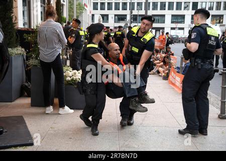 Berlin, Deutschland. 14. Juni 2023. Polizeibeamte bringen einen Aktivisten mit, um den Haupteingang zum 'Ritz Carlton' Hotel am Potsdamer Platz zu räumen. Mitglieder der Klimagruppe Last Generation saßen vor dem Haupteingang des Ritz-Carlton Hotels und einige friedlich aufgestellte Banner. Kredit: Paul Zinken/dpa/Alamy Live News Stockfoto