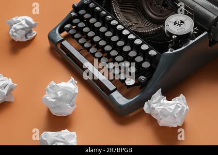 Vintage-Schreibmaschine mit zerknittertem Papier auf orangefarbenem Hintergrund Stockfoto