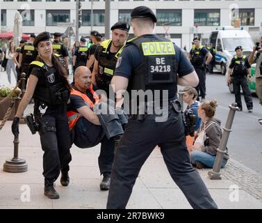 Berlin, Deutschland. 14. Juni 2023. Polizeibeamte bringen einen Aktivisten mit, um den Haupteingang zum 'Ritz Carlton' Hotel am Potsdamer Platz zu räumen. Mitglieder der Klimagruppe Last Generation saßen vor dem Haupteingang des Ritz-Carlton Hotels und einige friedlich aufgestellte Banner. Kredit: Paul Zinken/dpa/Alamy Live News Stockfoto