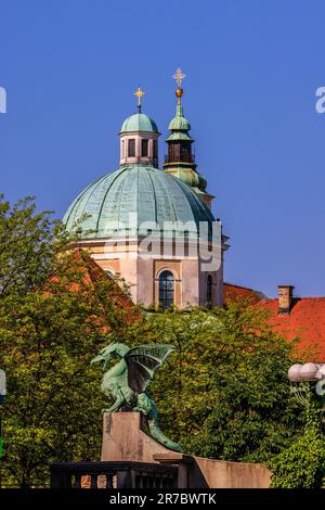 Die grünen Kuppeln der kathedrale von ljubljana über der grünen Drachenstatue auf der berühmten Drachenbrücke von ljubljana Stockfoto