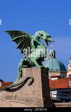 Die grüne Drachenstatue auf der Drachenbrücke von ljubljana, die das Kreuz auf der grünen Kuppel der Kathedrale von ljubljana verschlingen wird Stockfoto