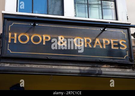 London, Großbritannien - März 2. 2023: Das Schild über dem Eingang zum öffentlichen Haus Hoop and Grapes - ein denkmalgeschütztes Gebäude der Kategorie II in der Aldgate High Street Stockfoto