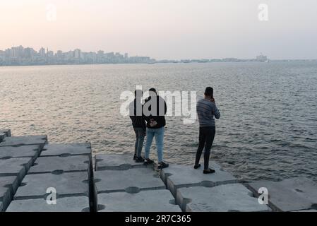 Alexandria, Ägypten. Dezember 1. 2022 Junge ägyptische Männer stehen auf großen Betonblöcken, die zum Schutz der Mittelmeerküstenstadt Alexan entworfen wurden Stockfoto