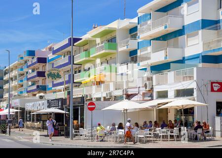 Mehrfarbige Apartments, Cafés und Restaurants auf der Avenue Infante de Sagres, Quarteira, Algarve, Portugal Stockfoto