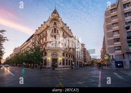 Edificio Banco Central Building und Gran Via de Colon Street bei Sonnenuntergang - Granada, Andalusien, Spanien Stockfoto