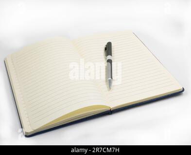 Ein offenes Notizbuch mit festem Einband und einem Stift darauf, mit Kopierbereich Stockfoto