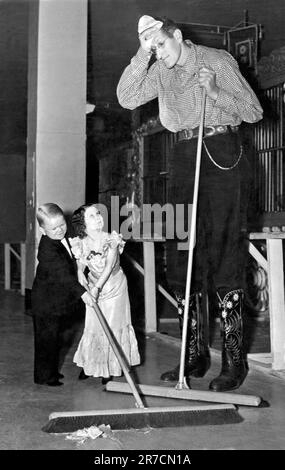 Vereinigte Staaten: c. 1938. Robert Wadlow, der größte Mann der Welt, teilt sich mit zwei Mitgliedern der Doll-Familie während der Tour mit den Ringling Brothers/Barnum & Bailey Circus ihre Pflichten. Stockfoto