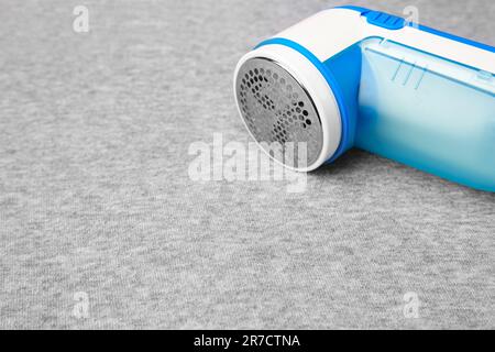 Moderner Rasierer auf hellgrauem Tuch mit Fusseln, Nahaufnahme. Platz für Text Stockfoto