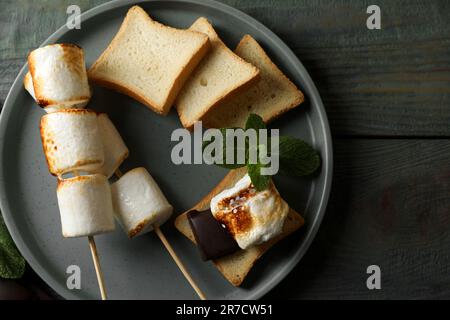 Köstliches Sandwich mit gerösteten Marshmallows und Schokolade auf grauem Holztisch, flach liegend Stockfoto