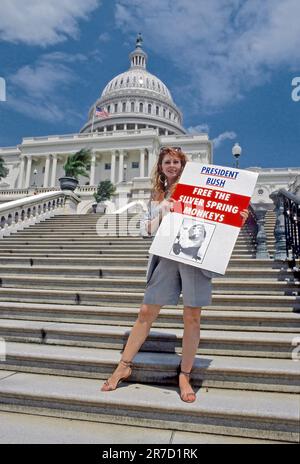 WASHINGTON DC - 10. JUNI 1990 Schauspielerin Cassandra Peterson (auch bekannt als Elvira, Herrin der Dunkelheit) hält ein Protestschild, das die Silver Spring Monkeys auf den Stufen des US Capitol während des protestmarsches gegen die Tierrechte darstellt. Stockfoto