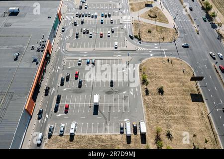 Blick von oben auf die Autos auf dem Parkplatz in der Nähe des Einkaufszentrums. Luftaufnahme von der fliegenden Drohne. Stockfoto