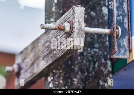 Rostig an Mutter, Schraube und Unterlegscheibe für die langfristige Befestigung an der alten Holzplatte. Stockfoto