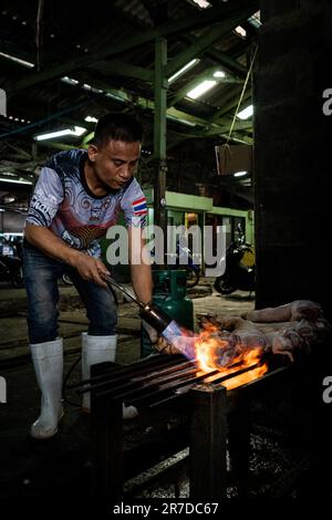 Bangkok, Thailand. 15. Juni 2023. Ein Verkäufer fackelt Schweinefüße auf dem Khlong Toey Wet Market ab. Das tägliche Leben in Bangkok, Thailand, hat sich die Wirtschaft erholt, wobei das Finanzministerium eine wirtschaftliche Expansion von 2,6 % im letzten Jahr und von 3,6 % in diesem Jahr ausgeht, wobei der internationale Tourismus ein Schlüsselfaktor für die wirtschaftliche Erholung nach der COVID-19-Pandemie ist. Kredit: Matt Hunt/Neato/Alamy Live News Stockfoto