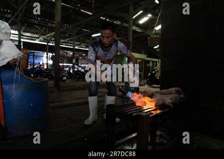 Bangkok, Thailand. 15. Juni 2023. Ein Verkäufer fackelt Schweinefüße auf dem Khlong Toey Wet Market ab. Das tägliche Leben in Bangkok, Thailand, hat sich die Wirtschaft erholt, wobei das Finanzministerium eine wirtschaftliche Expansion von 2,6 % im letzten Jahr und von 3,6 % in diesem Jahr ausgeht, wobei der internationale Tourismus ein Schlüsselfaktor für die wirtschaftliche Erholung nach der COVID-19-Pandemie ist. Kredit: Matt Hunt/Neato/Alamy Live News Stockfoto