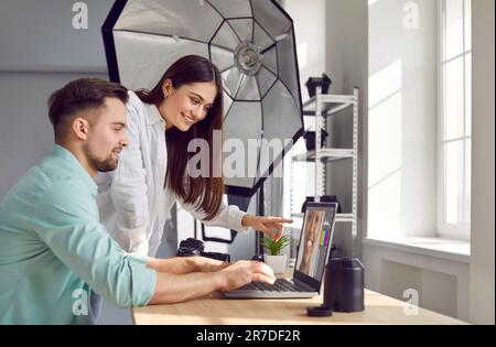 Fotograf und Model wählen Fotos auf dem Laptop zusammen aus Stockfoto