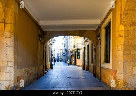 Oviedo, Spanien - 12. Februar 2023: Eine Fußgängerunterführung in Gelb und Weiß. Die Leute laufen auf dem Fußweg, umgeben von Gebäuden Stockfoto