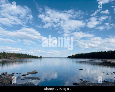 Die beschauliche Seeszene in Schweden spiegelt den Himmel und umgibt die umliegenden Bäume bei Tageslicht. Stockfoto