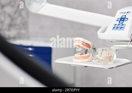 Nahaufnahme des Hintergrundes des Zahnmodells mit Werkzeugen am zahnärztlichen Stuhl in der zahnärztlichen Klinik, Kopierraum Stockfoto