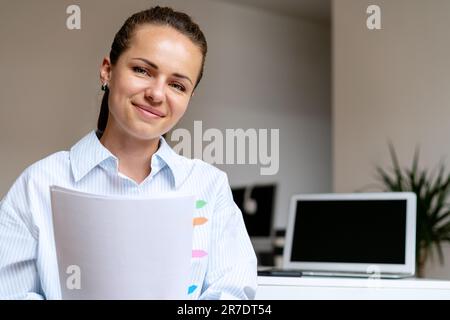 Eine brünette Frau im Büro mit Dokumenten in der Hand. Stockfoto