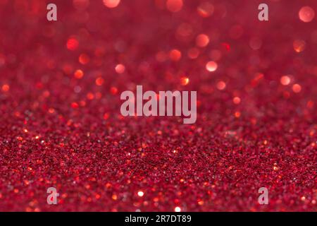 Unscharfer roter glitzernder Hintergrund. Glänzender roter Hintergrund. Weihnachtskarte. Der Lichtschein. Schöne, helle Festtage mit abstrakter roter Glitzerstruktur. Glänzend Stockfoto