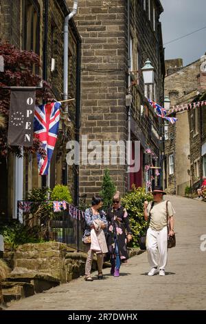 Haworth, West Yorkshire, Großbritannien. Drei Besucher von Haworth machen einen Spaziergang entlang der Main Street in diesem beliebten Dorf in West Yorkshire. Stockfoto
