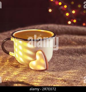 Herzförmige Tasse Kaffee und Lebkuchen. Seichte dof. Alte Tasse Kaffee mit herzförmigen Keksen auf Leinenstruktur. Stockfoto