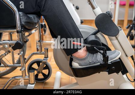 Eine nicht erkennbare ältere Frau macht Pedalübungen vom Rollstuhl im Krankenhaus. Hochwertiges Foto. Stockfoto