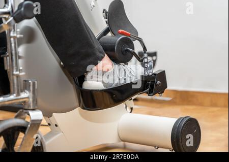 Eine nicht erkennbare ältere Frau macht Pedalübungen vom Rollstuhl im Krankenhaus. Hochwertiges Foto. Stockfoto