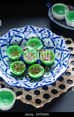 Asiatisches Speisekonzept thailändischer alkalischer Pandan-Reiskuchen in thailändischer Keramikplatte auf schwarzem Hintergrund mit Kopierbereich Stockfoto