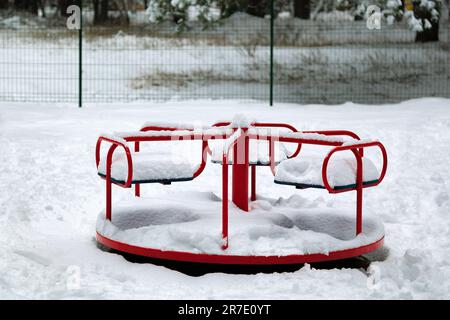 Schnee auf einer Kinderschaukel nach starkem Schneefall. Schaukelkarussell. Urbane Szene des Stadtlebens im Winter bei Schneesturm. Winter auf dem Spielplatz. Spielen Stockfoto