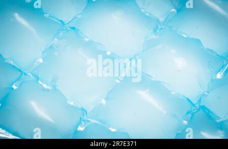 Blaue Eisbeutel aus Plastikverpackungen zum Einfrieren von Wasser zu Hause. Eiswürfel im Kunststoffbeutel-Texturhintergrund. Gefrierschrank für Eiswürfel Stockfoto