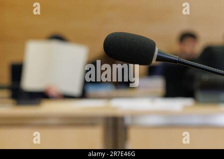 Bielefeld, Deutschland. 15. Juni 2023. Zwei Angeklagte sitzen hinter einem Mikrofon in einem Gerichtssaal. Der Prozess wegen angeblichen Giftmordes beginnt vor dem Bezirksgericht Bielefeld. Die beiden Angeklagten sollen eine außereheliche Beziehung gehabt haben. Gemeinsam sollen die Frau aus Bielefeld (50) und ihr Freund aus Hamburg (45) den Plan umgesetzt haben, den Ehemann am 30. April 2022 mit einem Gift zu töten. Laut der Anklage legte die Frau eine giftige Mischung in ein Glas Wasser neben das Bett des Mannes. Kredit: Friso Gentsch/dpa/Alamy Live News Stockfoto