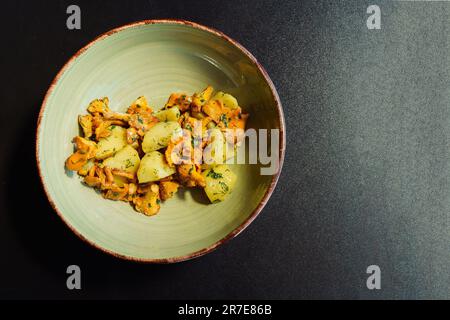 Blick von oben auf eine Schüssel mit gebratenen Pfifferlingen, gekochten Kartoffeln, Petersilie und Dill. Frisches vegetarisches Mittagessen mit organischen, saisonalen, lokalen Produkten Stockfoto
