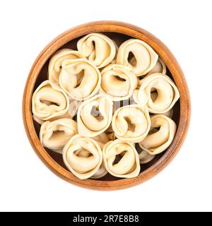 Ungekochte, getrocknete Tortellini in einer Holzschüssel. Industriell gefüllte Teigtaschen, italienische Pasta, mit unverwechselbarer Form. Stockfoto