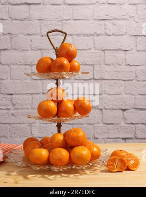 Antike Kristallschale Mit Kleinen Orangen. Dessert mit Backsteinwand im Hintergrund Stockfoto