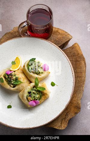 Die leckeren drei Pfannkuchen mit Füllung auf einem weißen Teller mit einem Glas Tee Stockfoto