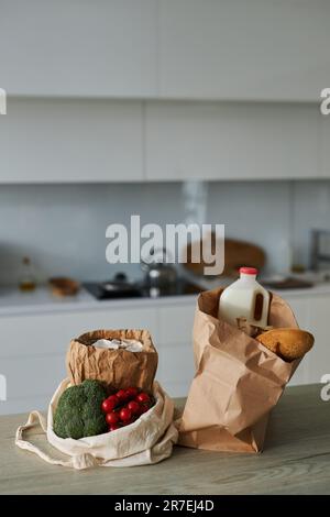 Vertikales Bild von Papiertüten mit Produkten auf dem Tisch in der Küche zu Hause Stockfoto