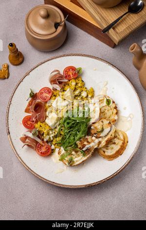 Eine Nahaufnahme eines Tellers mit frisch zubereitetem Frühstück mit einer bunten Auswahl an Zutaten wie Eiern, Pilzen, Tomaten, Zwiebeln und Kräutern Stockfoto