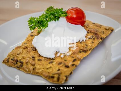 Ein Teller mit frisch gebackenem Knäckebrot mit Frischkäse-Belag. Stockfoto