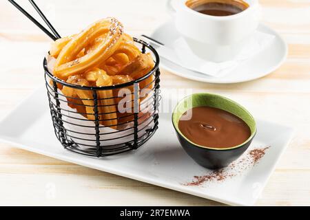 Dessert mit Schokoladensirup und einer Tasse Kaffee auf weißem Holzhintergrund. Frisches Frühstück. Stockfoto